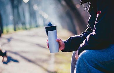 Man sitting on bench holding coffee